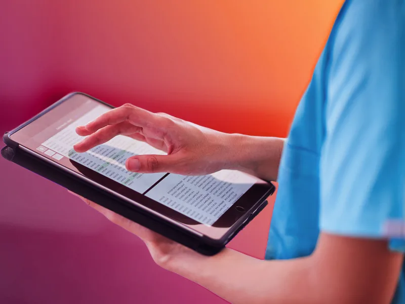 Healthcare professional using a tablet to review clinical research data and patient records.