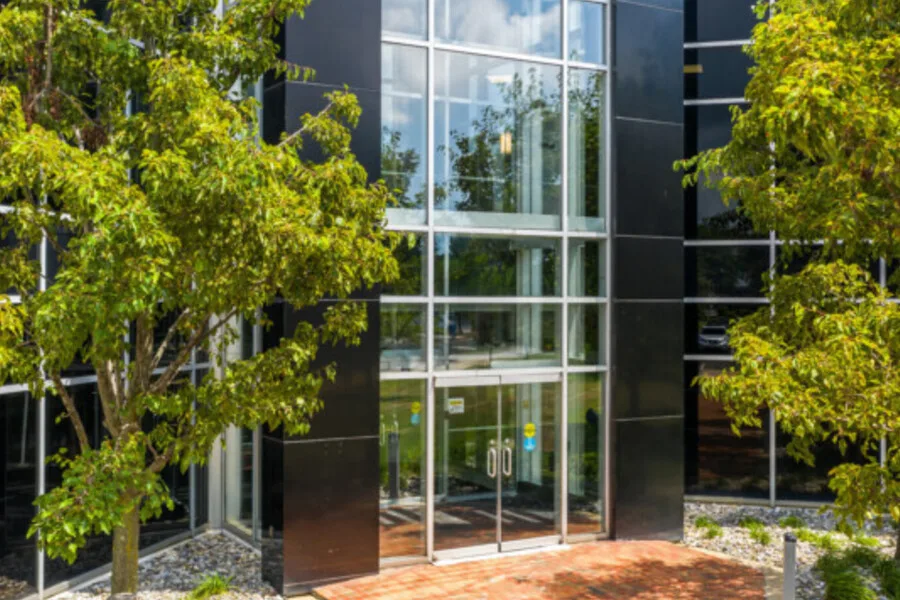Glass-front building entrance framed by trees.