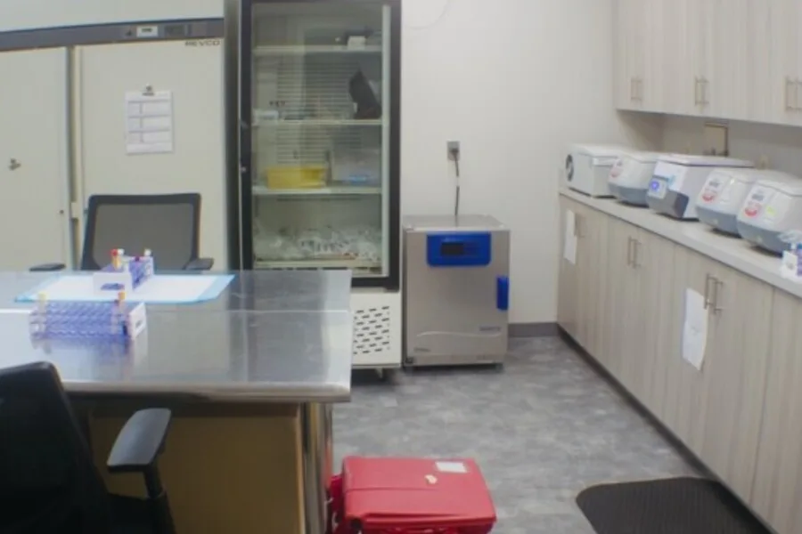 Laboratory processing room with stainless worktable, freezers, and benchtop equipment.”