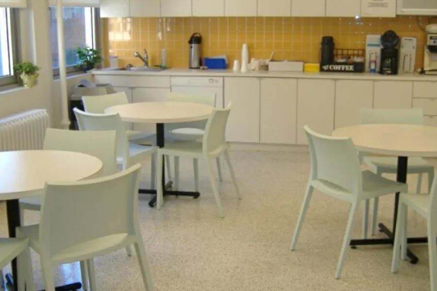 Staff kitchen and break area with round tables and yellow tile backsplash
