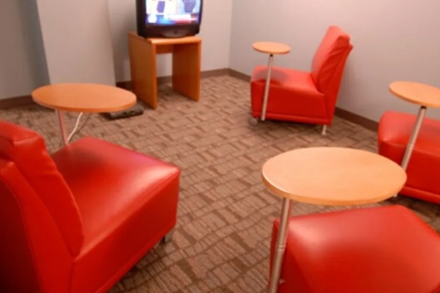 Small media room with red lounge chairs and individual tablet tables facing a TV.