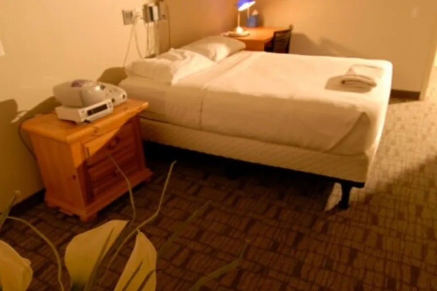Private patient room with single bed, nightstand, desk, and medical equipment.